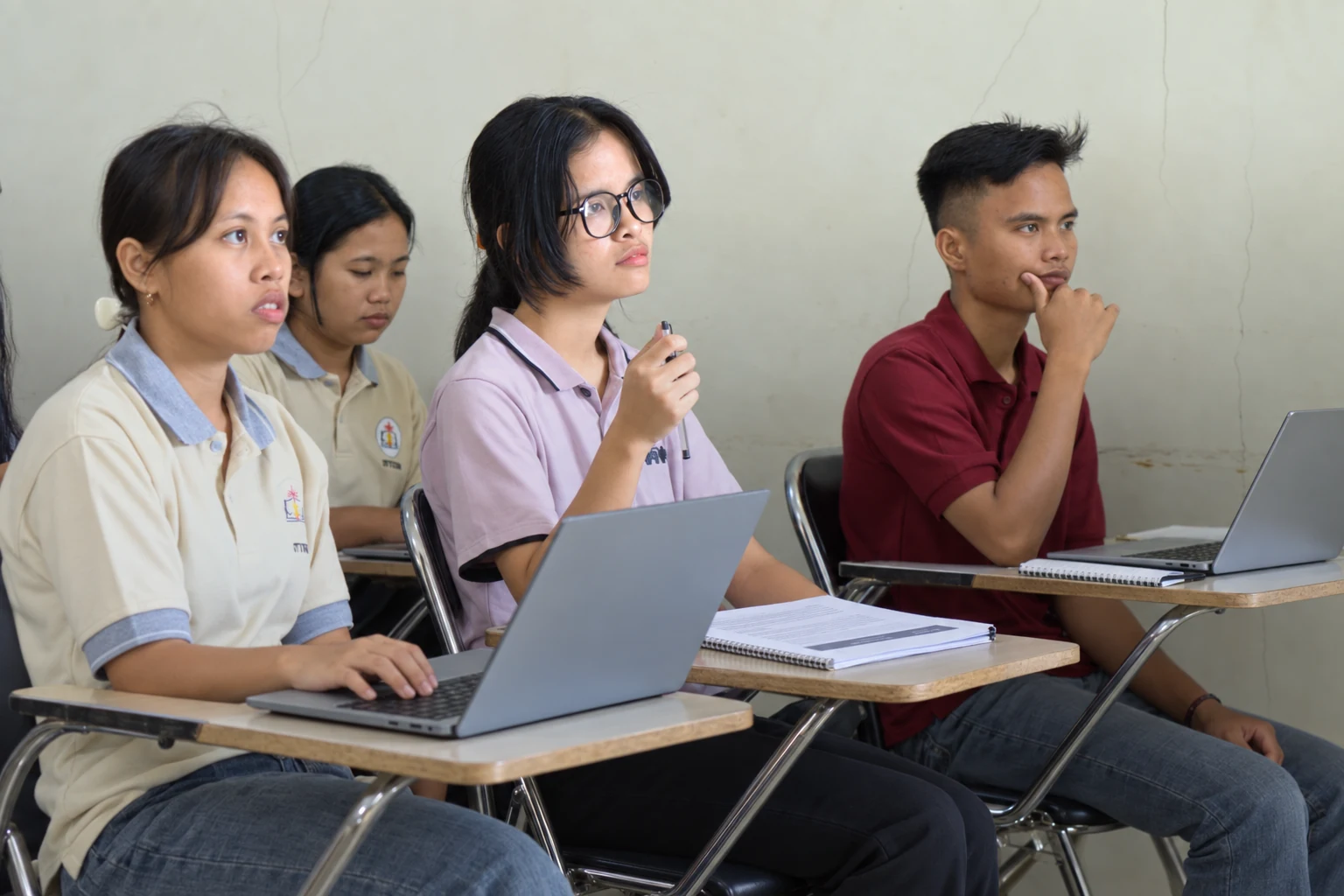Mahasiswa menggunakan laptop dan menyiapkan catatan serta berkas tugas.